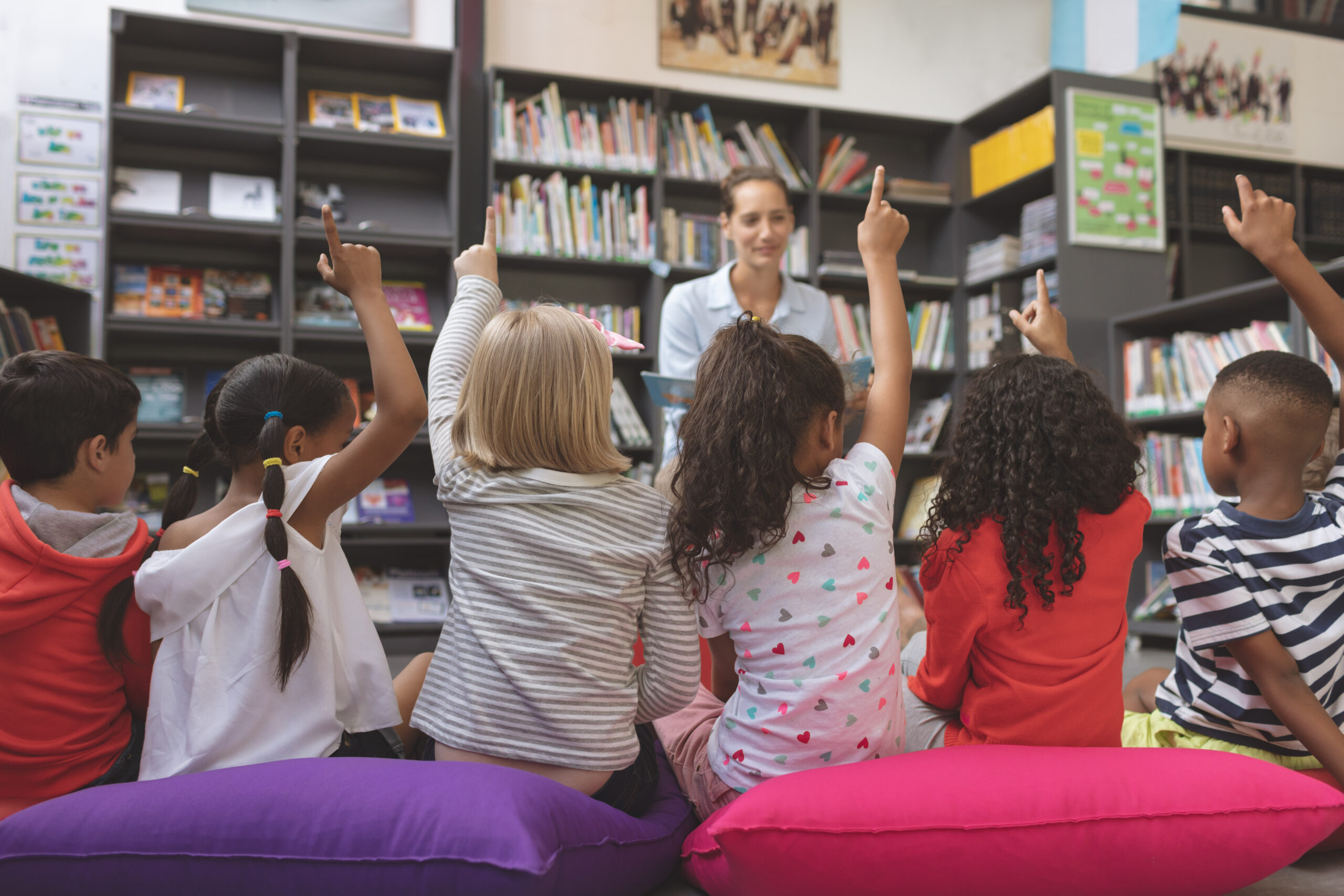 Rear view of school children raising their hands at a library answering a question. Below is a blog post titled "Breaking Down the Benefits of the Federal Educational Choice for Children Act For Homeschoolers".