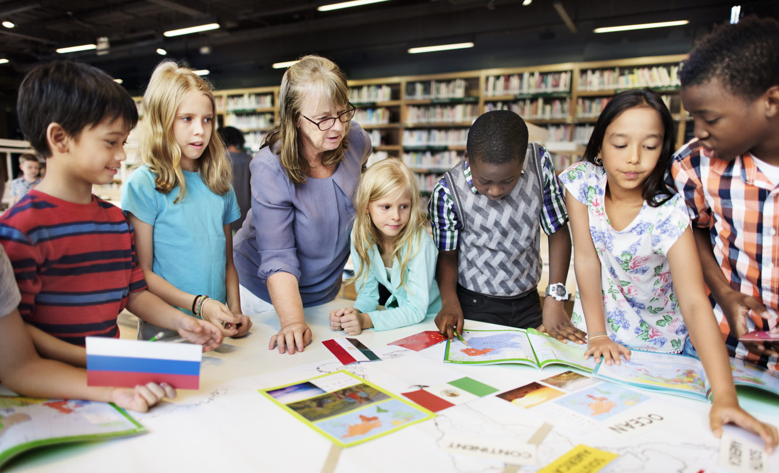 Class of students and teacher gather around a table reviewing state flags, indicating the use of ESA funds. Title at bottom reads:Arkansas’ Educational Freedom Accounts (EFA) Undergoes Major Updates
