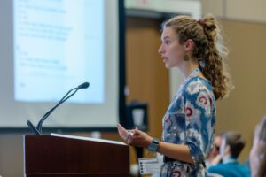 A young girl speaks at a podium in a conference room, with a projected screen behind her. Text overlay reads "Connecticut's House Bill 5468 Draws Legal Challenges From HSLDA"